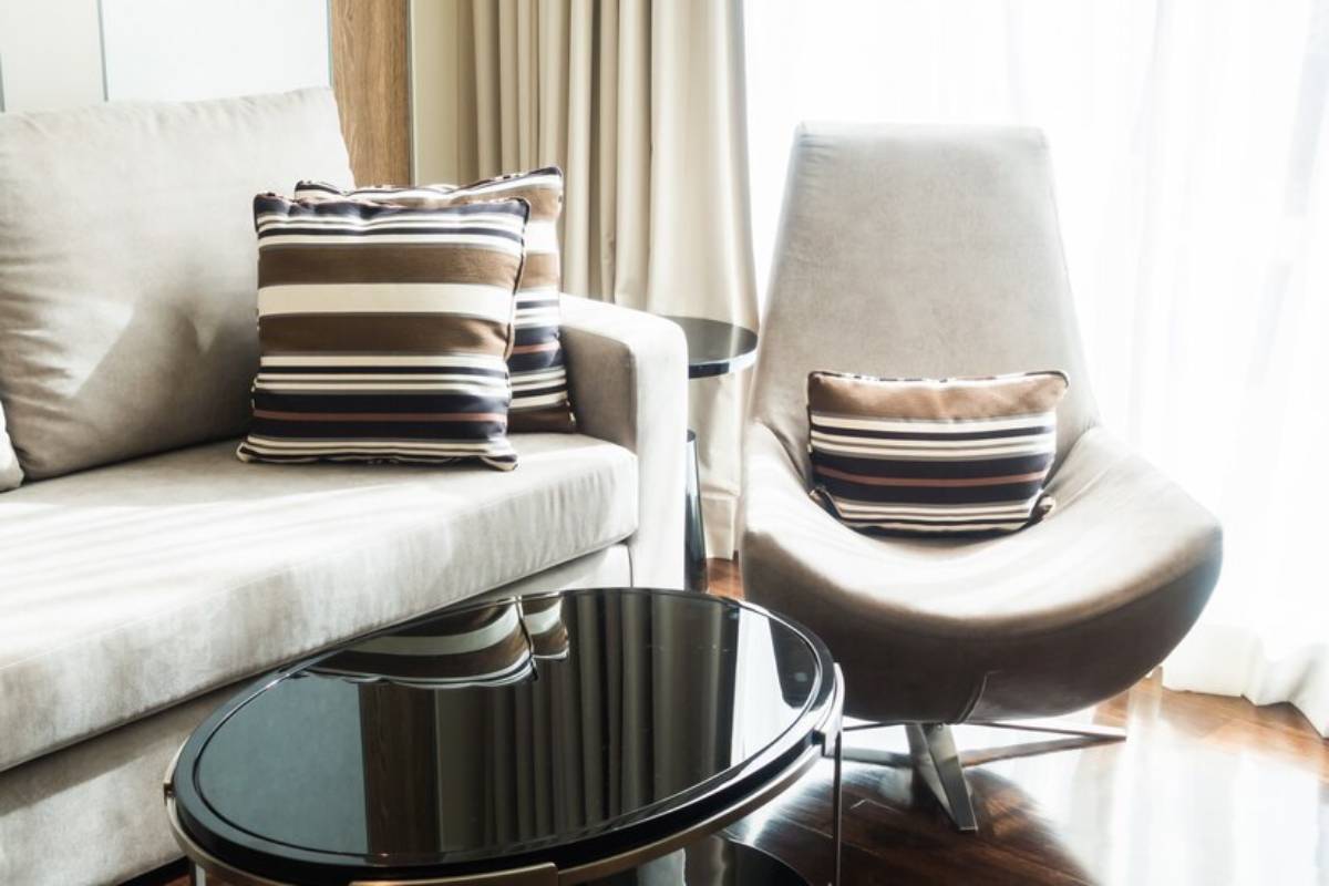 A modern living area featuring a light gray sofa with striped cushions, a sleek black coffee table, and a stylish, curved lounge chair.